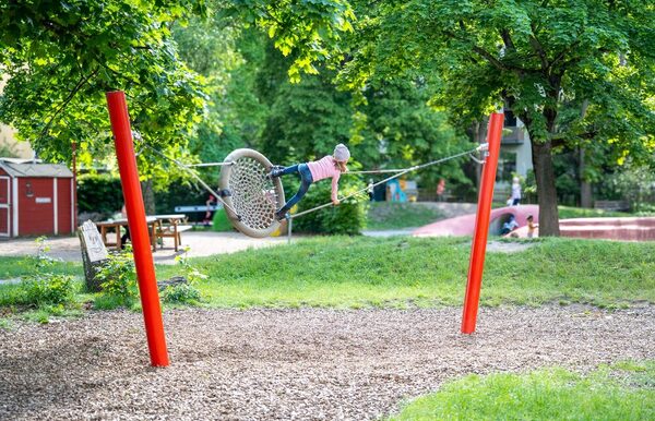 Kind schaukelt stehend auf der Nestschaukel im Freigelände der Kita
